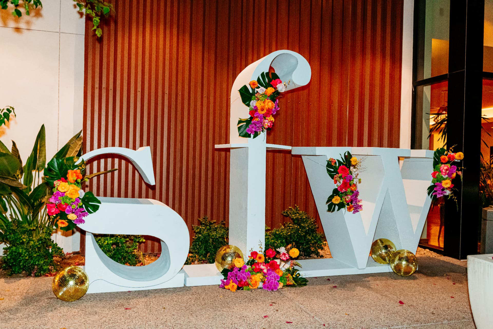 Giant white SFW letters dressed in tropical flowers and gold disco balls at Scottsdale Fashion Week