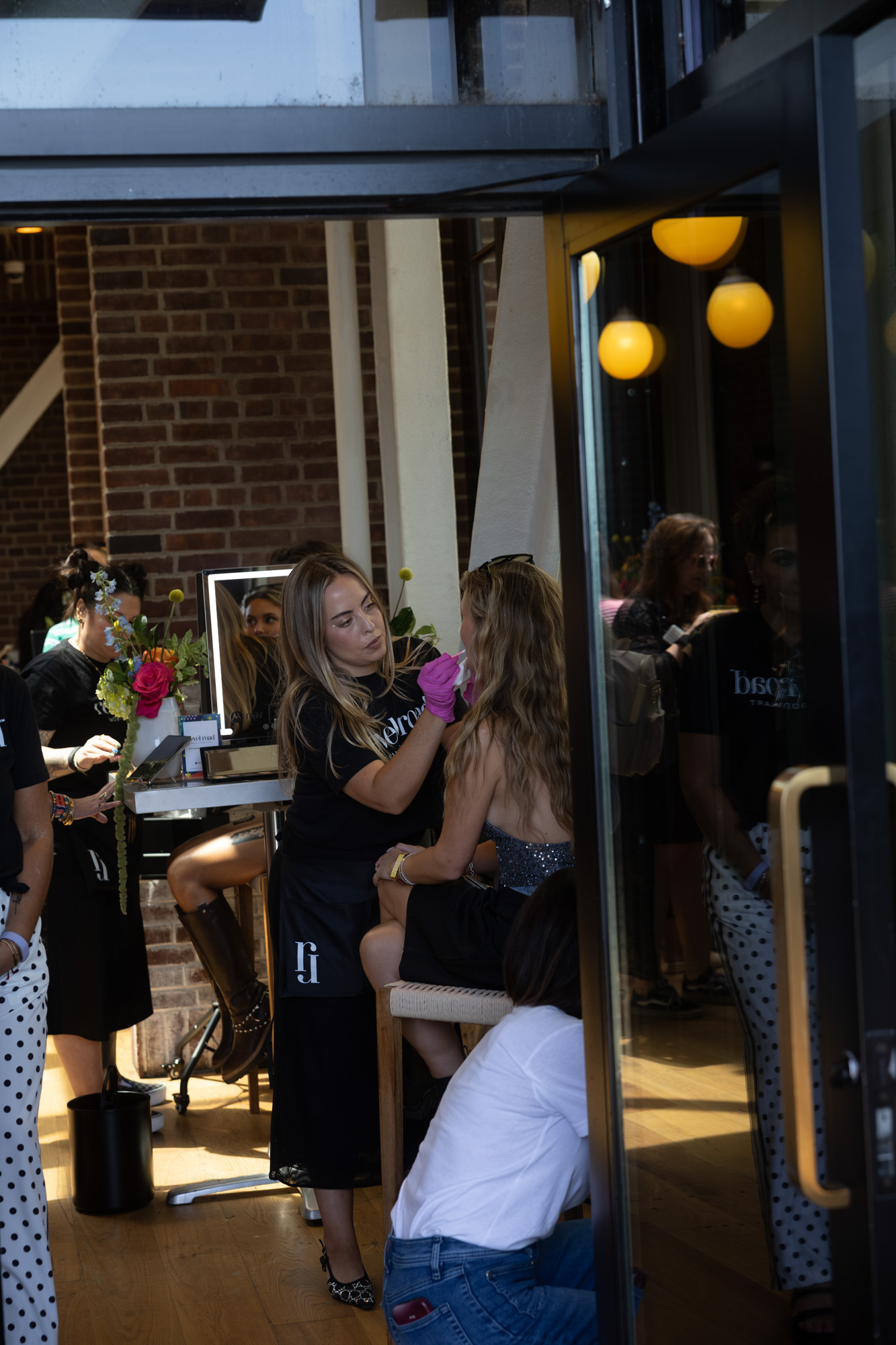 Revel Road artist in pink gloves applying body art to a seated guest at an event